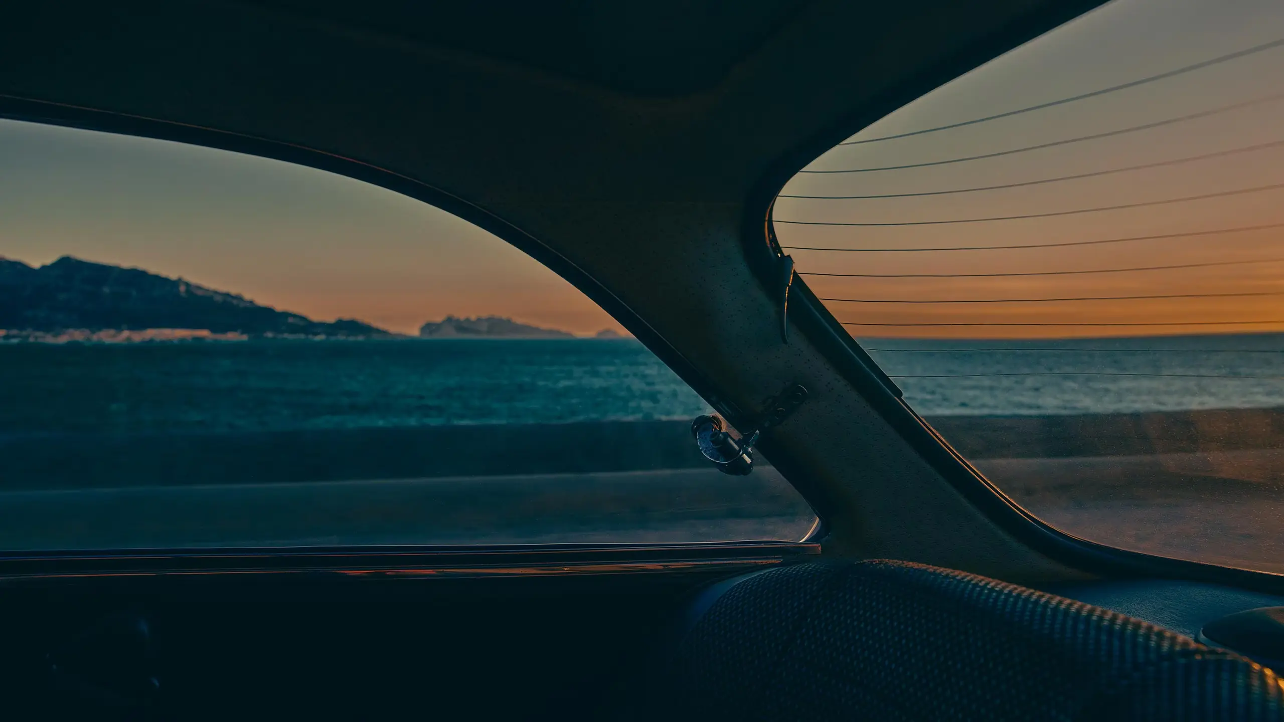 A car interior with a view of the ocean at sunset.